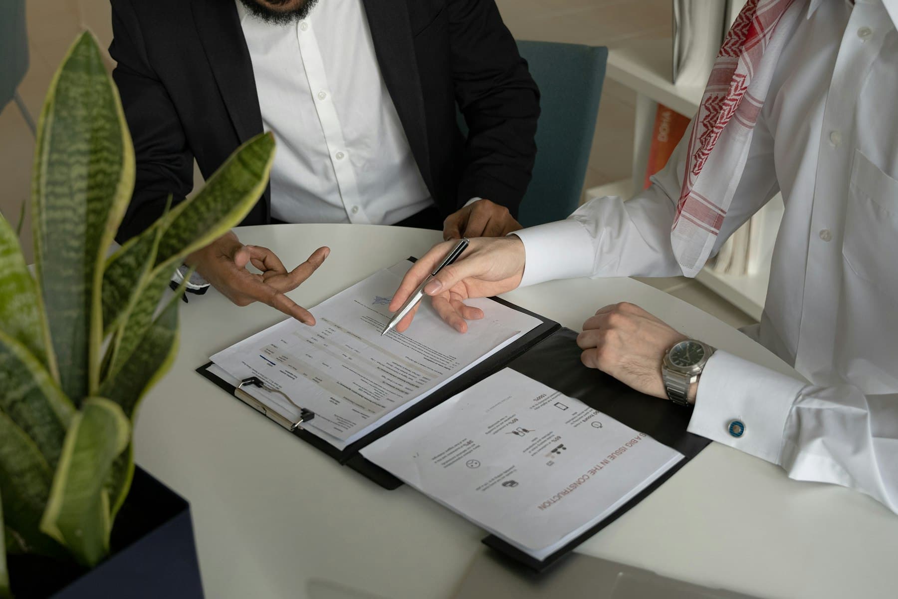 مستشار خليجي وصاحب شركة يقرآن مستندات الشركة معًا على طاولة مكتب — هذا هو التشخيص: قراءة الشركة كما هي بأرقامها